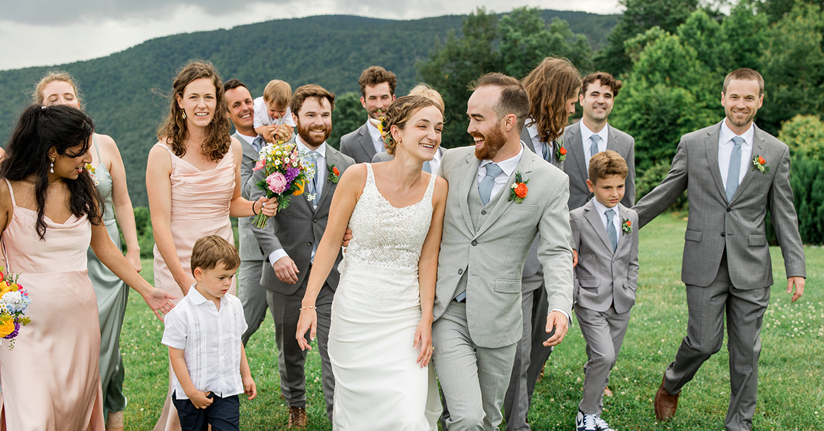 A couple walks with their wedding party against the blue ridge mountains at Sky Retreat wedding venue near Boone, NC