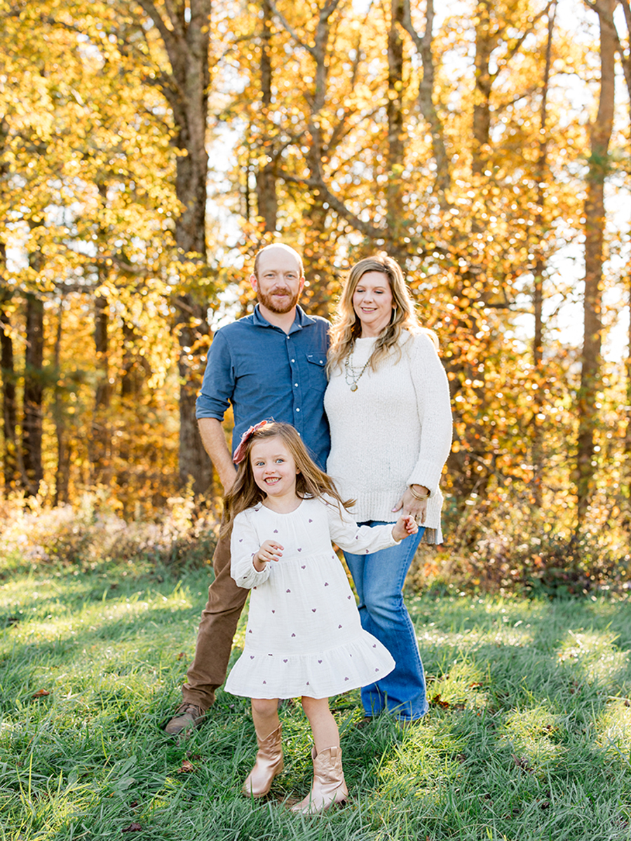 A girl spins and laughs in front of her parents during a fall family photo session on the Blue Ridge Parkway near Boone, NC.